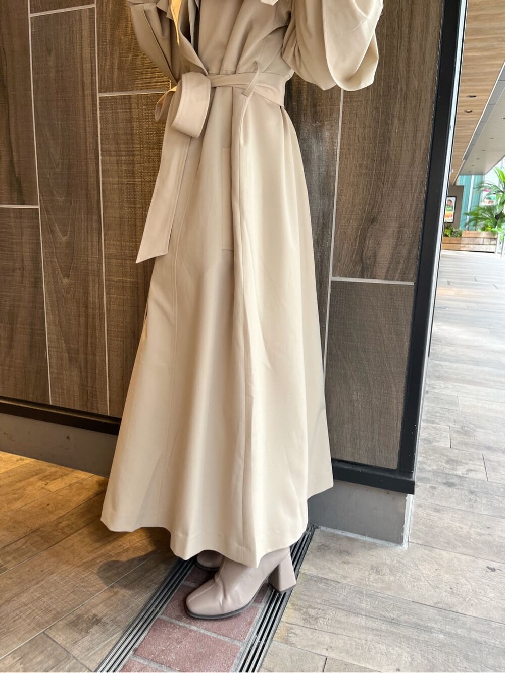 ベージュ系のトレンチコート、ベージュ系のブーツ、ベージュ系のスカートを着用したレディースの秋コーディネートの10枚目の写真