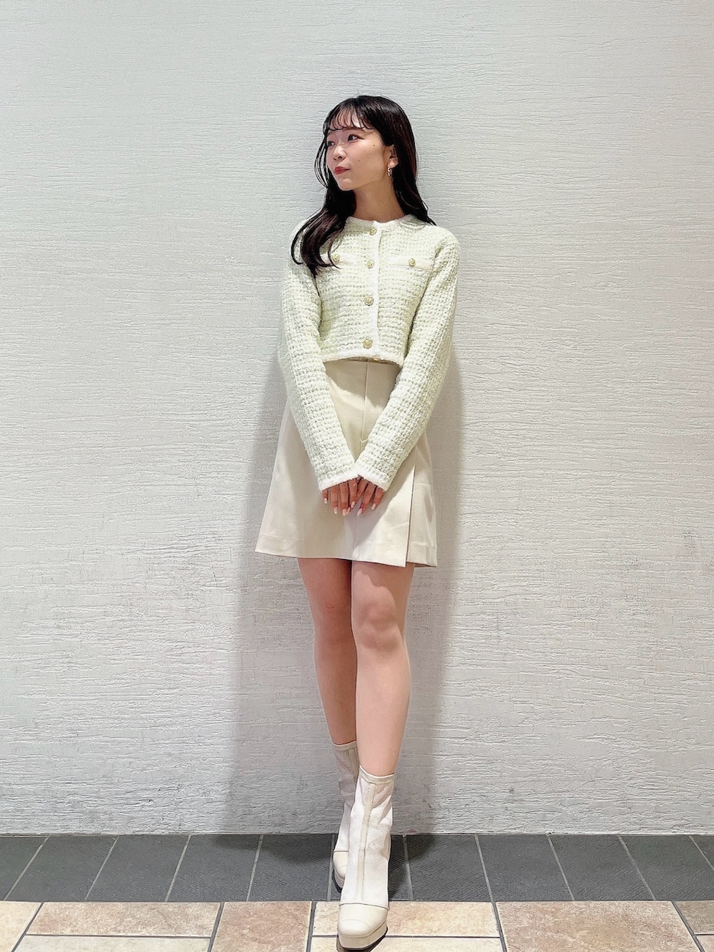 グリーン系のノーカラージャケット、ホワイト系のブーツ、ホワイト系のスカートを着用したレディースの冬コーディネートの2枚目の写真