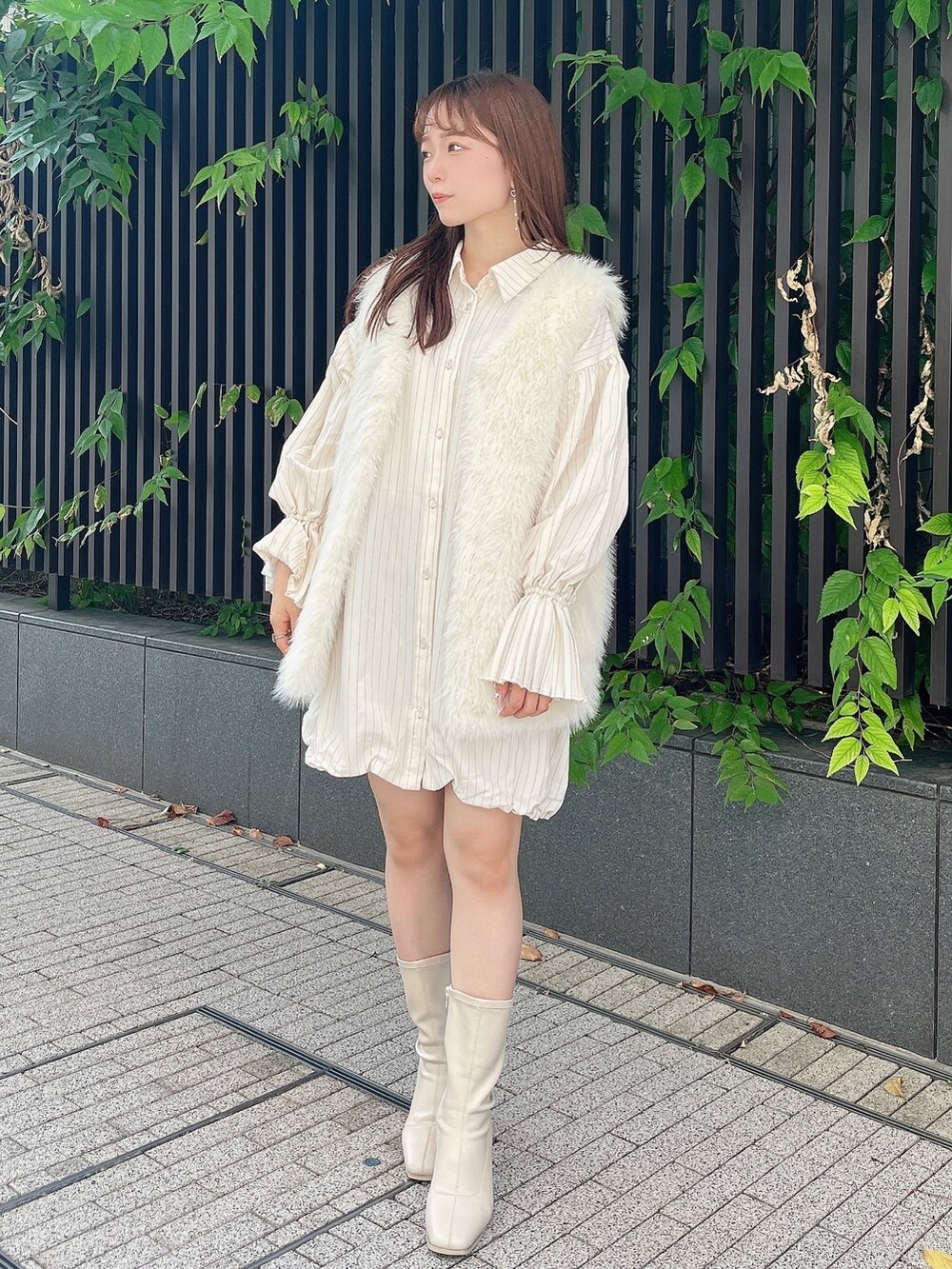 ホワイト系のベスト、ベージュ系のワンピース、ホワイト系のブーツを着用したレディースの秋コーディネートの6枚目の写真