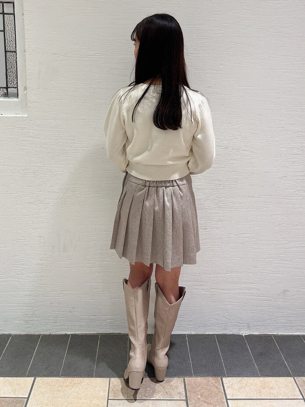 ホワイト系のニット/セーター、ベージュ系のスカート、ベージュ系のブーツを着用したレディースの冬コーディネートの4枚目の写真