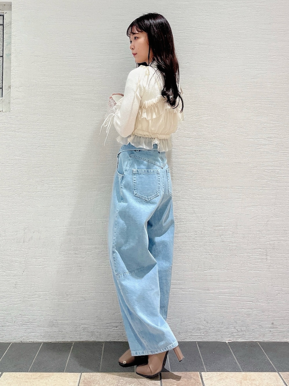 ベージュ系のブーツ、ブルー系のデニムパンツ、ベージュ系のキャミソールを着用したレディースの冬コーディネートの3枚目の写真