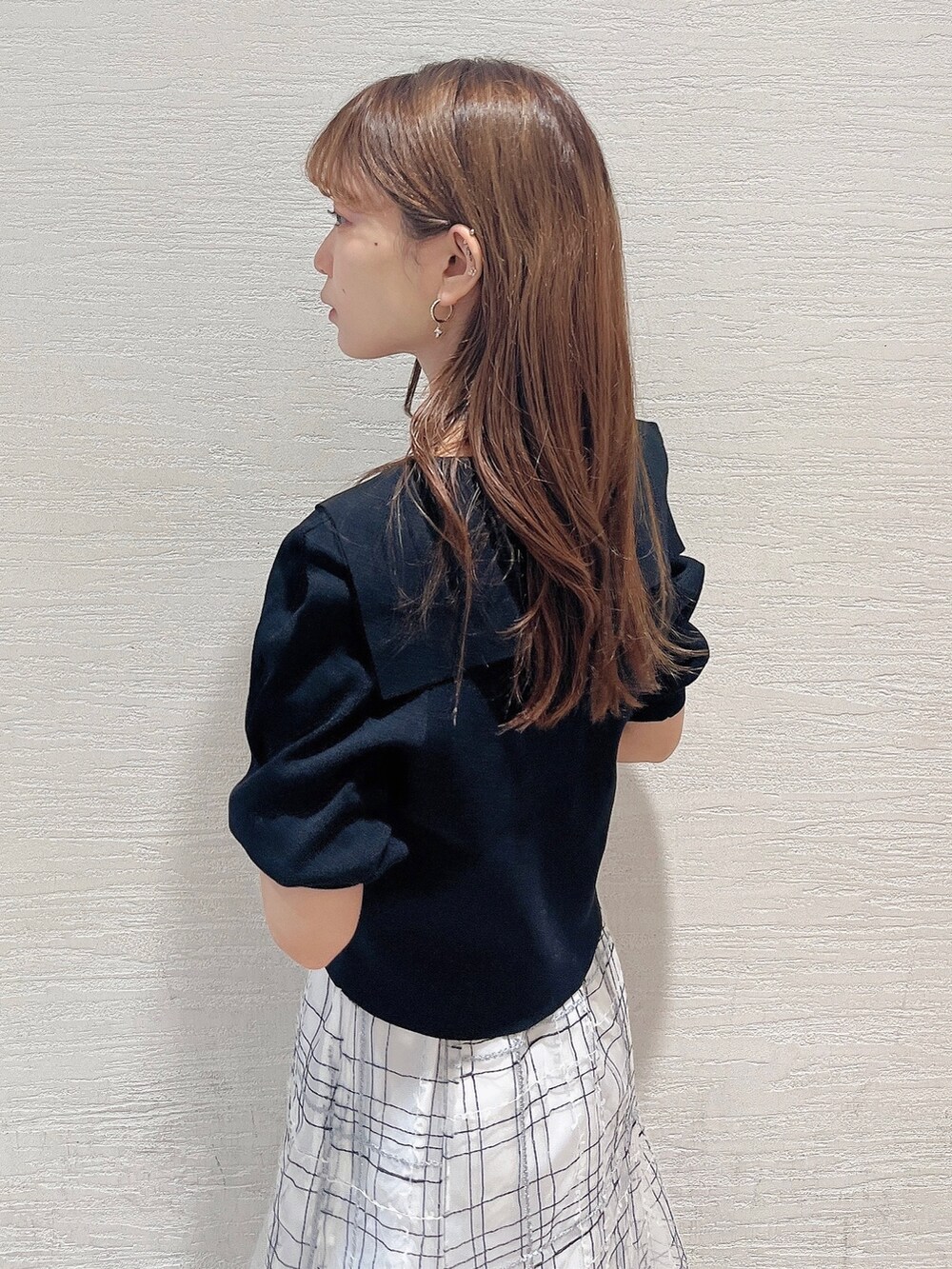 ブラック系のニット/セーター、ホワイト系のスカート、ブラック系のローファーを着用したレディースの夏コーディネートの6枚目の写真