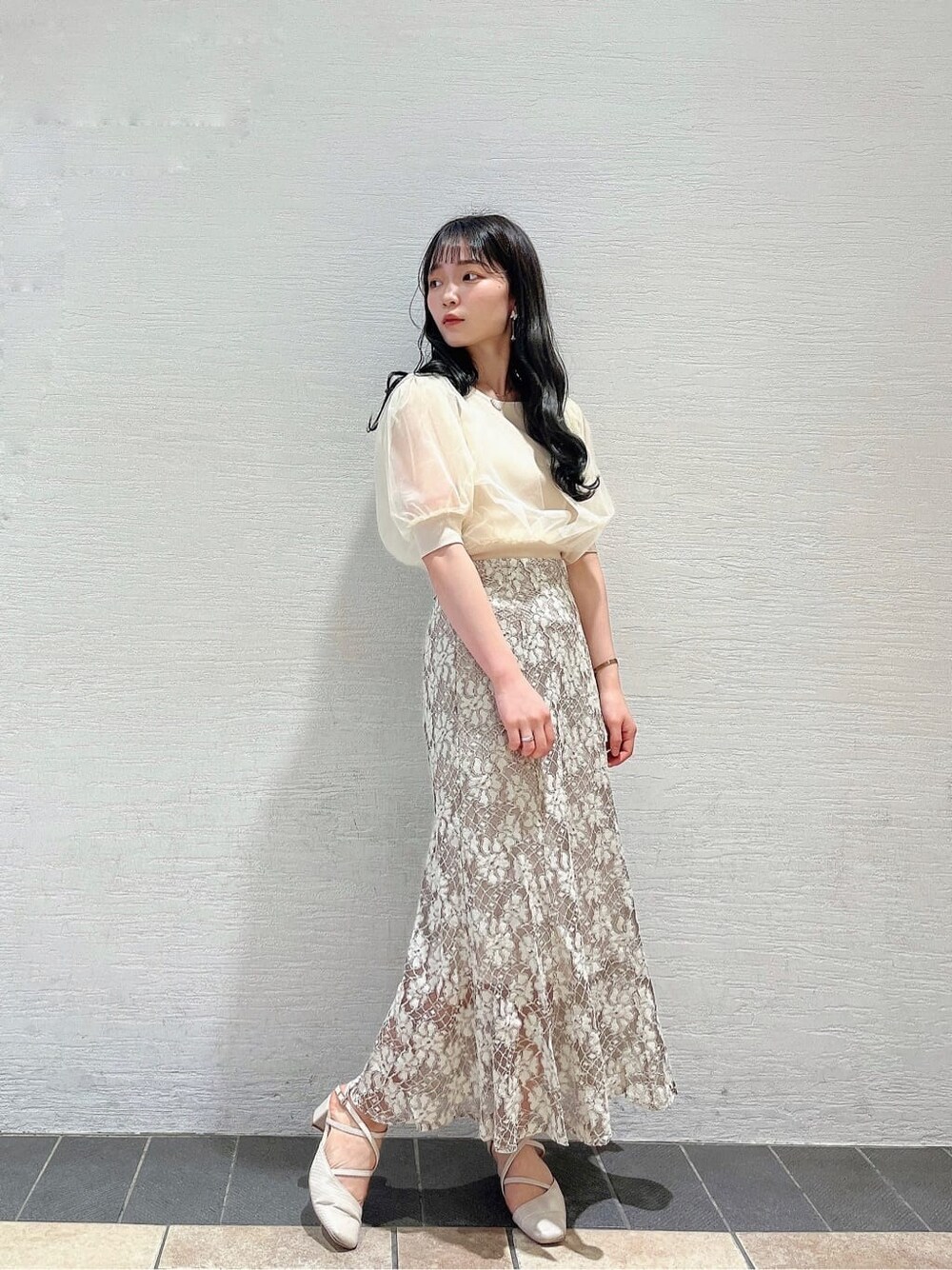 ベージュ系のスカート、ホワイト系のパンプス、ホワイト系のニット/セーターを着用したレディースの春コーディネートの3枚目の写真