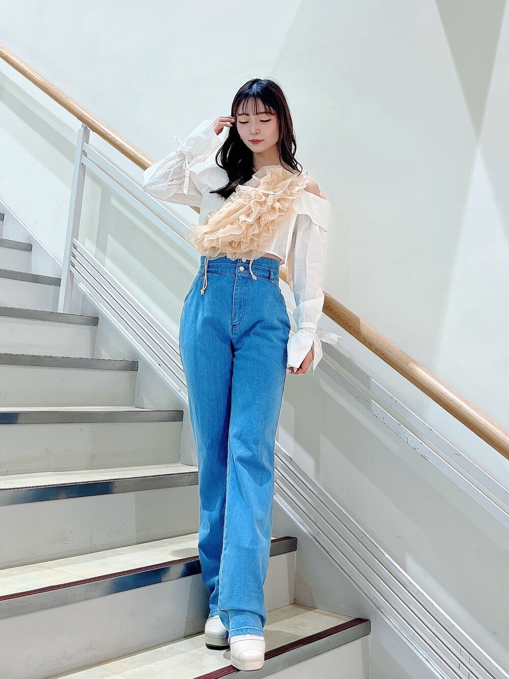 オレンジ系のベスト、ブルー系のデニムパンツ、ホワイト系のシャツ/ブラウスを着用したレディースの春コーディネートの3枚目の写真