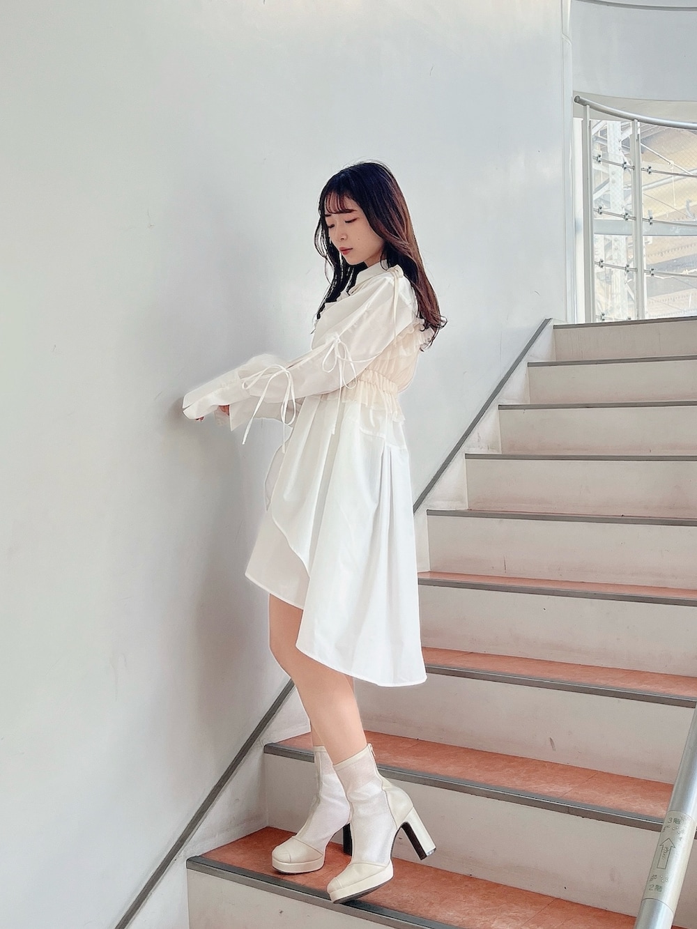 ベージュ系のキャミソール、ホワイト系のシャツワンピース、ホワイト系のブーツを着用したレディースの冬コーディネートの6枚目の写真