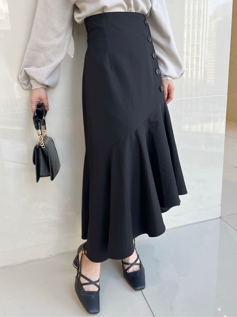 グレー系のニット/セーター、ブラック系のスカート、ブラック系のパンプスを着用したレディースの夏コーディネートの8枚目の写真