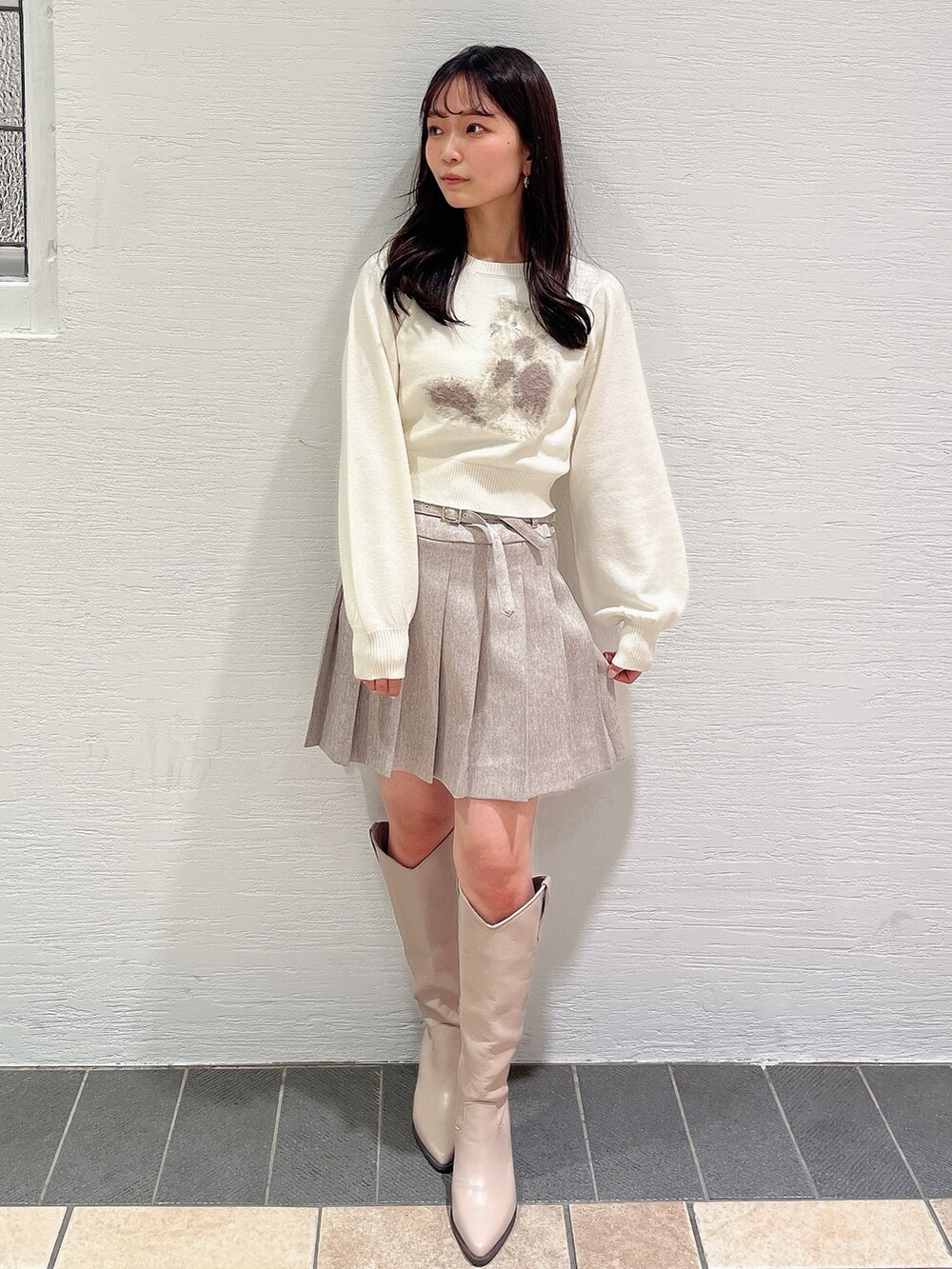 ホワイト系のニット/セーター、ベージュ系のスカート、ベージュ系のブーツを着用したレディースの冬コーディネートの2枚目の写真