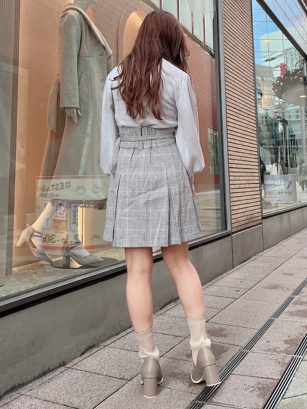 グレー系のニット/セーター、グレー系のスカート、ベージュ系のブーツを着用したレディースの冬コーディネートの3枚目の写真