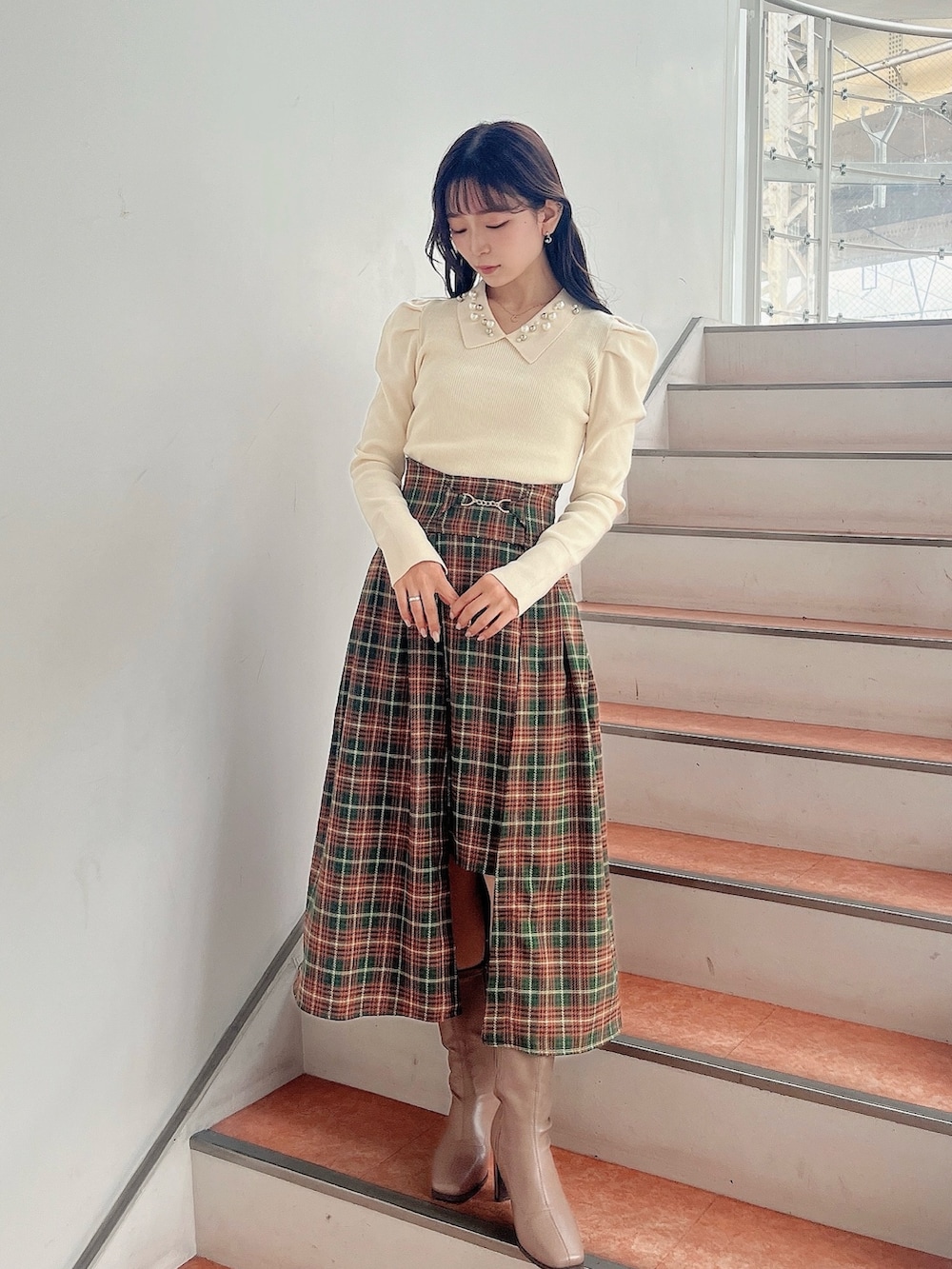 ホワイト系のニット/セーター、グリーン系のスカート、ベージュ系のブーツを着用したレディースの秋コーディネートの5枚目の写真