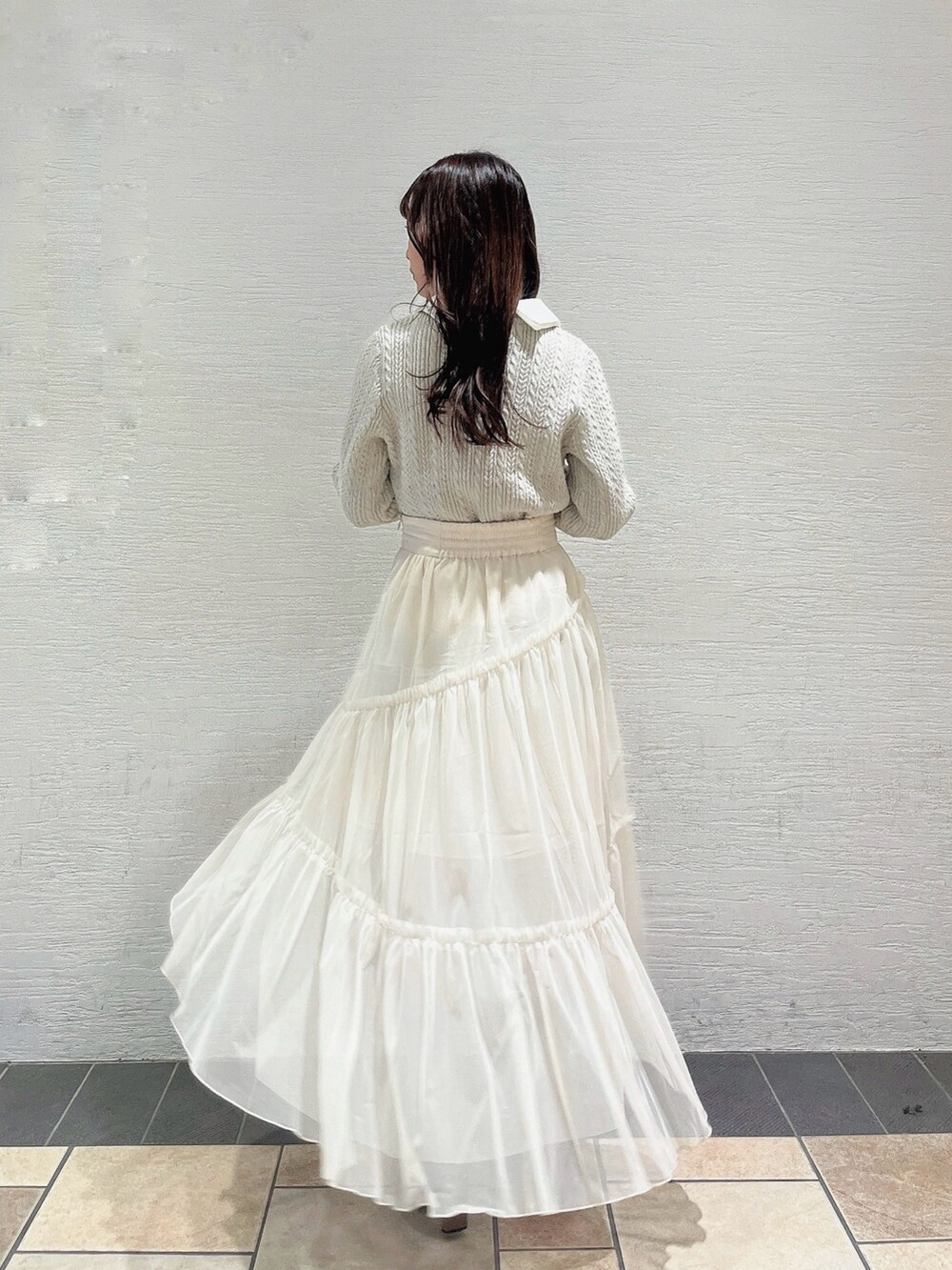 ベージュ系のニット/セーター、ホワイト系のスカート、ベージュ系のブーツを着用したレディースの冬コーディネートの4枚目の写真