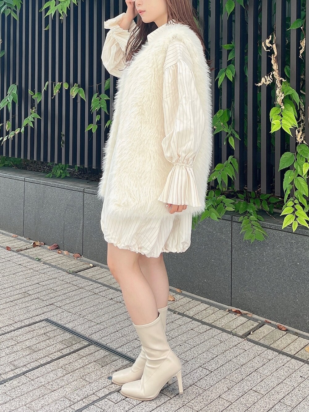 ホワイト系のベスト、ベージュ系のワンピース、ホワイト系のブーツを着用したレディースの秋コーディネートの4枚目の写真