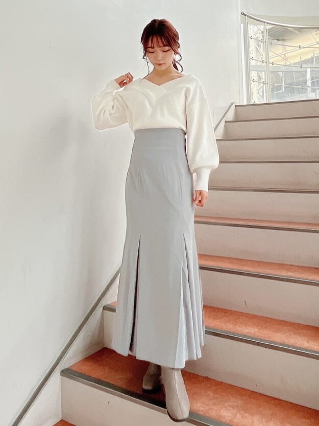 ベージュ系のブーツ、グレー系のスカート、ホワイト系のニット/セーターを着用したレディースの秋コーディネートの2枚目の写真