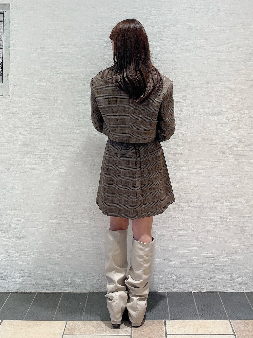 ベージュ系のブーツ、ブラウン系のスカート、ホワイト系のニット/セーターを着用したレディースの秋コーディネートの3枚目の写真