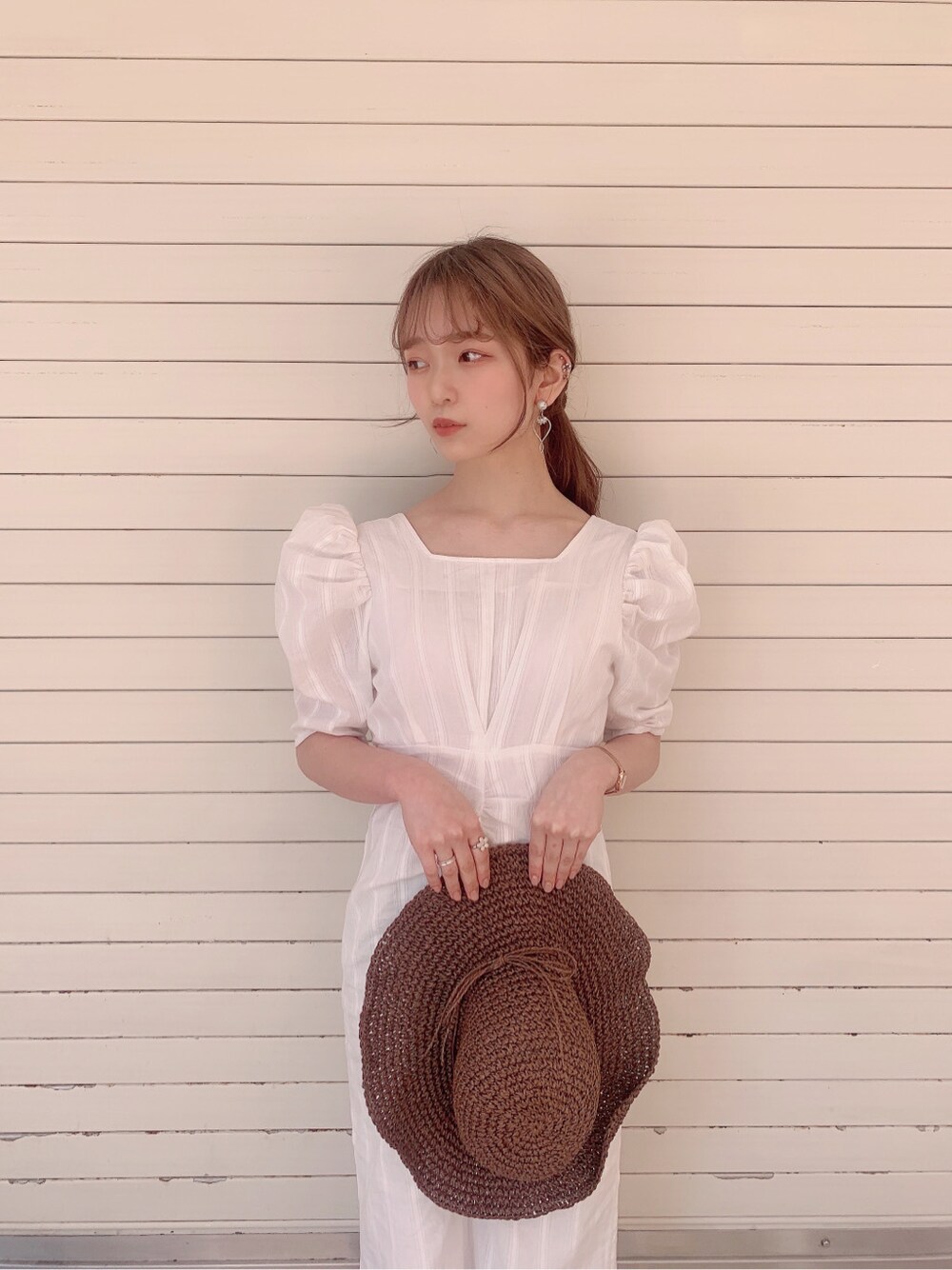 ホワイト系のワンピース、ベージュ系のサンダル、ブラウン系のハットを着用したレディースの春コーディネートの6枚目の写真