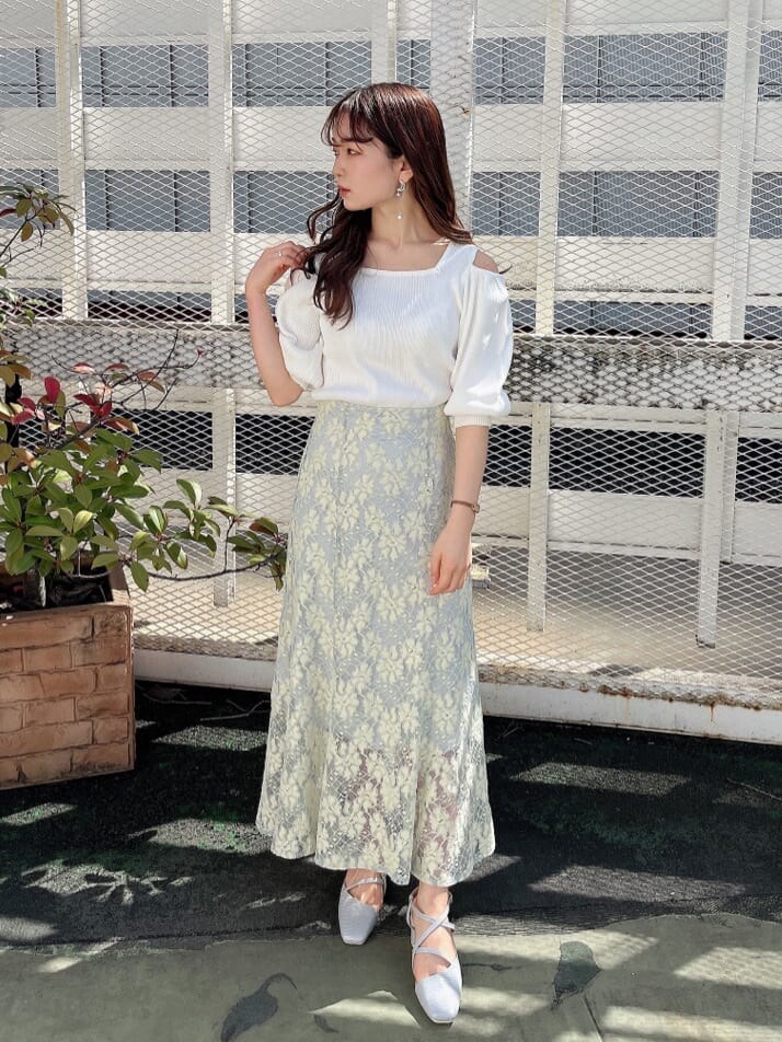 ブルー系のスカート、ホワイト系のニット/セーター、グレー系のパンプスを着用したレディースの春コーディネートの2枚目の写真