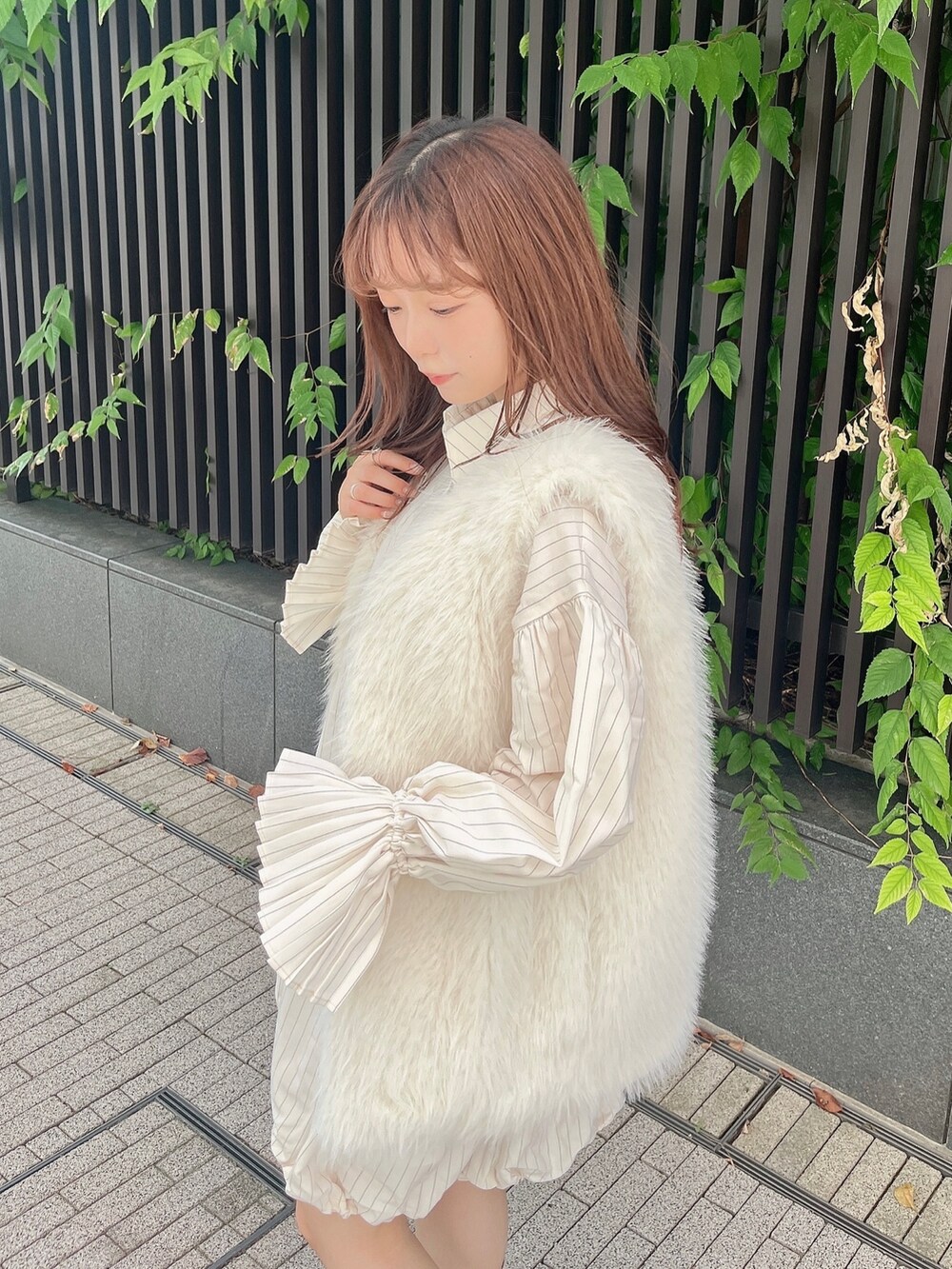 ホワイト系のベスト、ベージュ系のワンピース、ホワイト系のブーツを着用したレディースの秋コーディネートの7枚目の写真