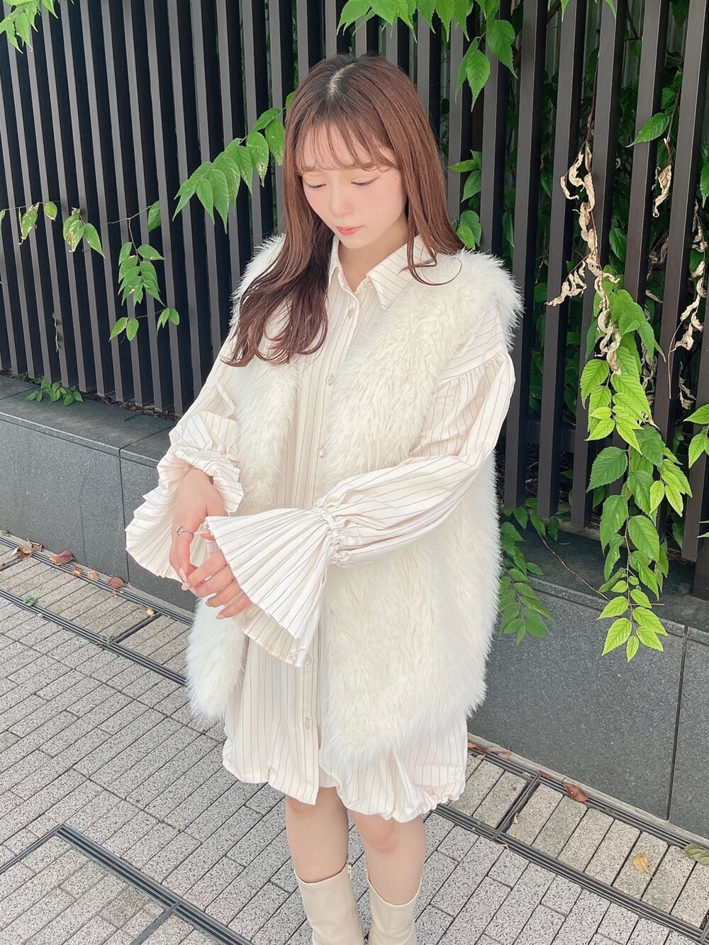 ホワイト系のベスト、ベージュ系のワンピース、ホワイト系のブーツを着用したレディースの秋コーディネートの9枚目の写真