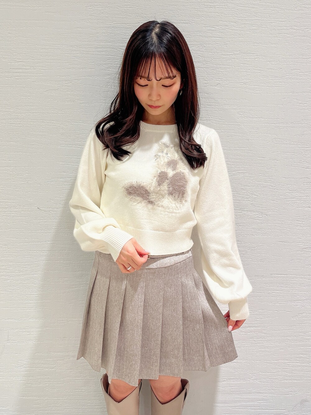 ホワイト系のニット/セーター、ベージュ系のスカート、ベージュ系のブーツを着用したレディースの冬コーディネートの6枚目の写真