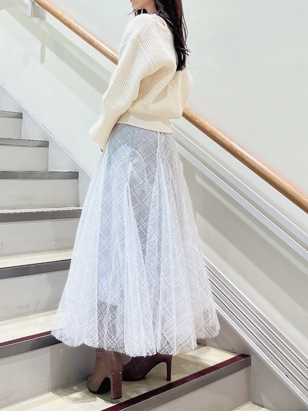 ホワイト系のニット/セーター、グレー系のスカート、ベージュ系のブーツを着用したレディースの冬コーディネートの3枚目の写真