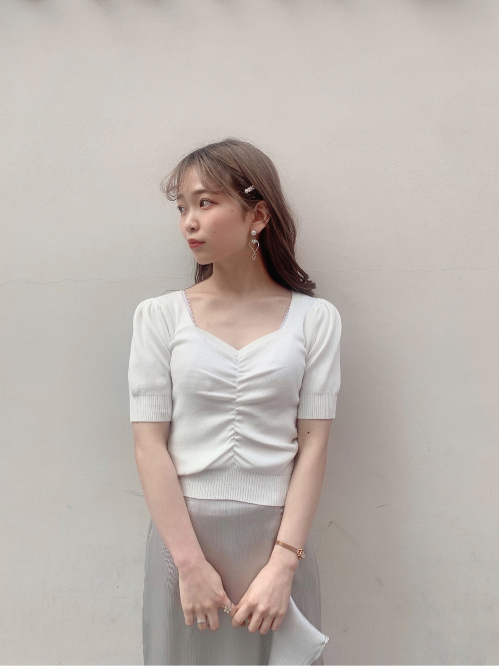 グレー系のスカート、ブルー系のサンダル、ホワイト系のニット/セーターを着用したレディースの春コーディネートの7枚目の写真