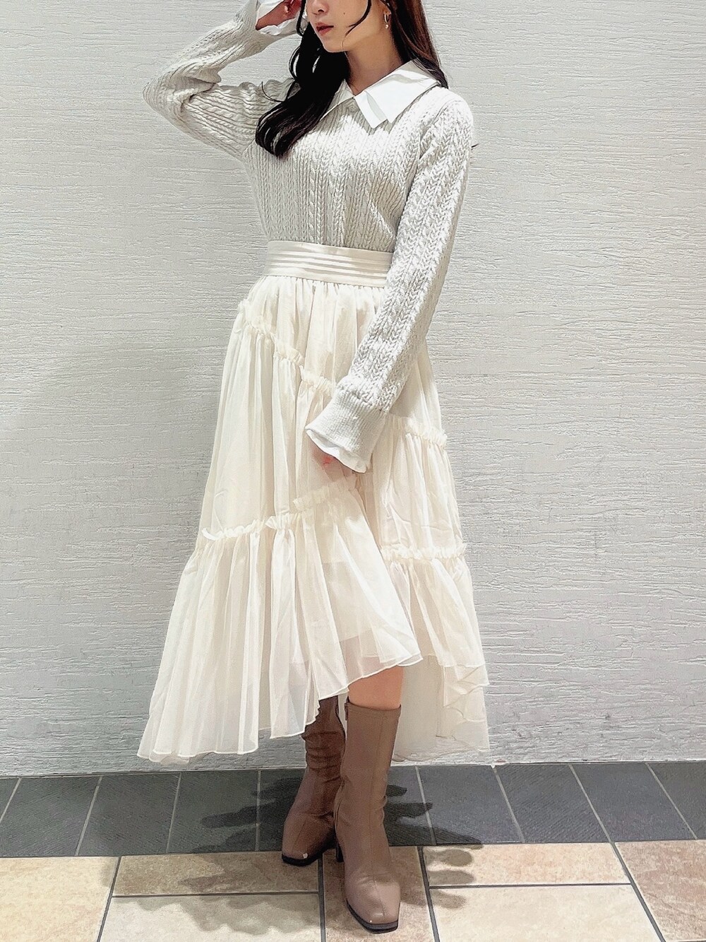 ベージュ系のニット/セーター、ホワイト系のスカート、ベージュ系のブーツを着用したレディースの冬コーディネートの2枚目の写真