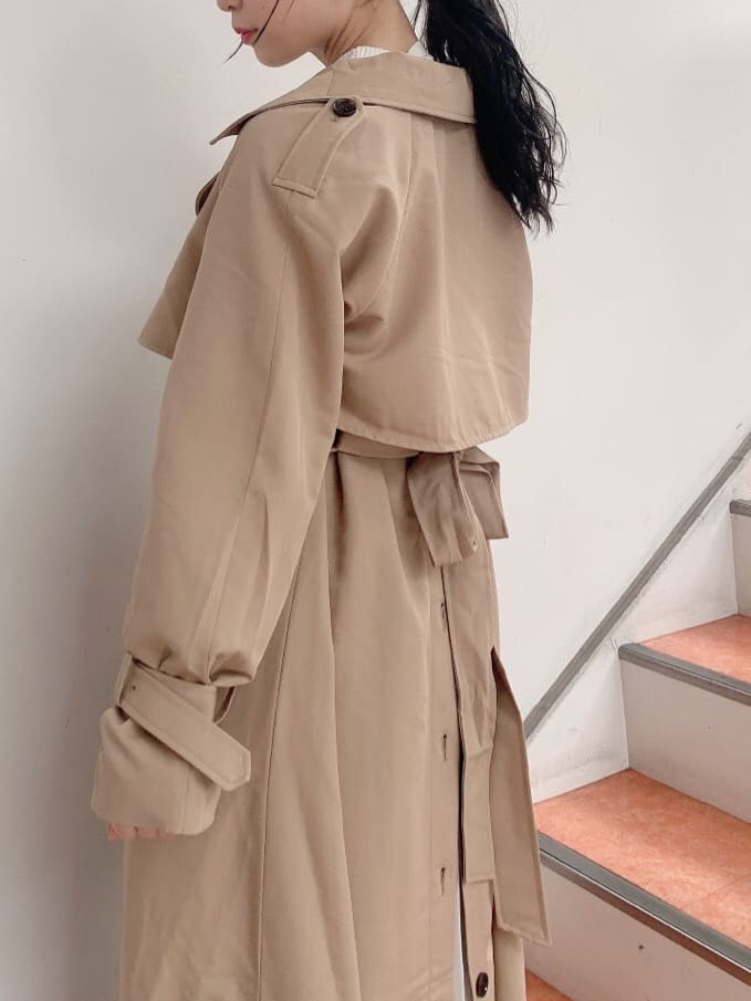 ベージュ系のトレンチコート、ベージュ系のブーツ、その他のジャンパースカートを着用したレディースの秋コーディネートの4枚目の写真