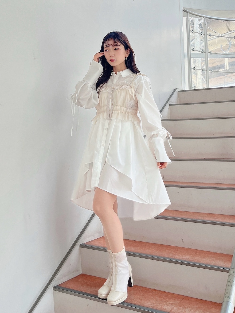 ベージュ系のキャミソール、ホワイト系のシャツワンピース、ホワイト系のブーツを着用したレディースの冬コーディネートの2枚目の写真