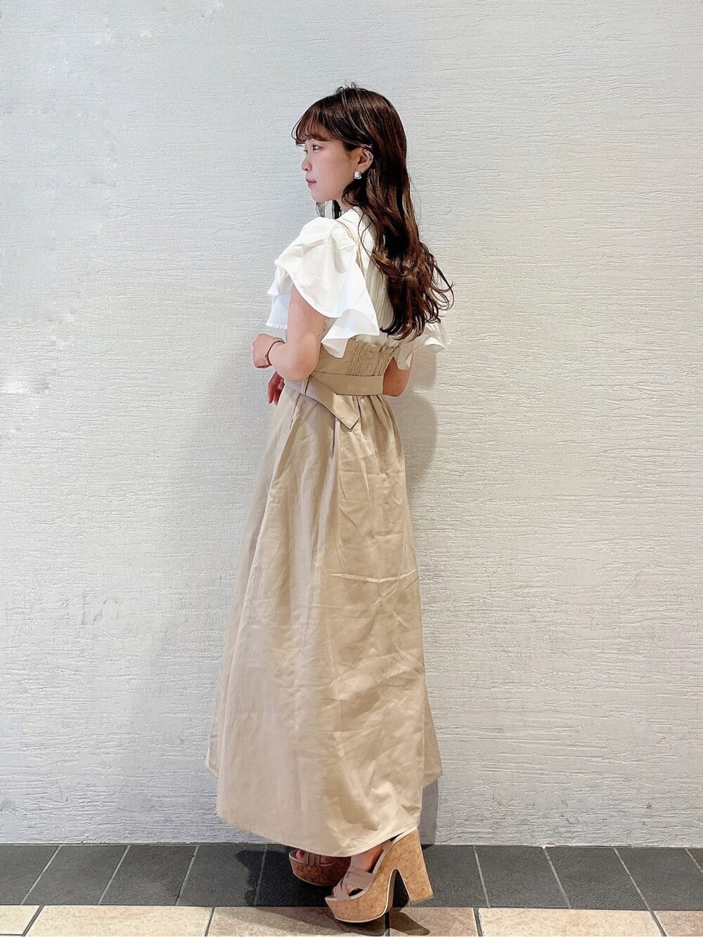 ベージュ系のサンダル、ベージュ系のワンピース、ホワイト系のTシャツ/カットソーを着用したレディースの春コーディネートの2枚目の写真