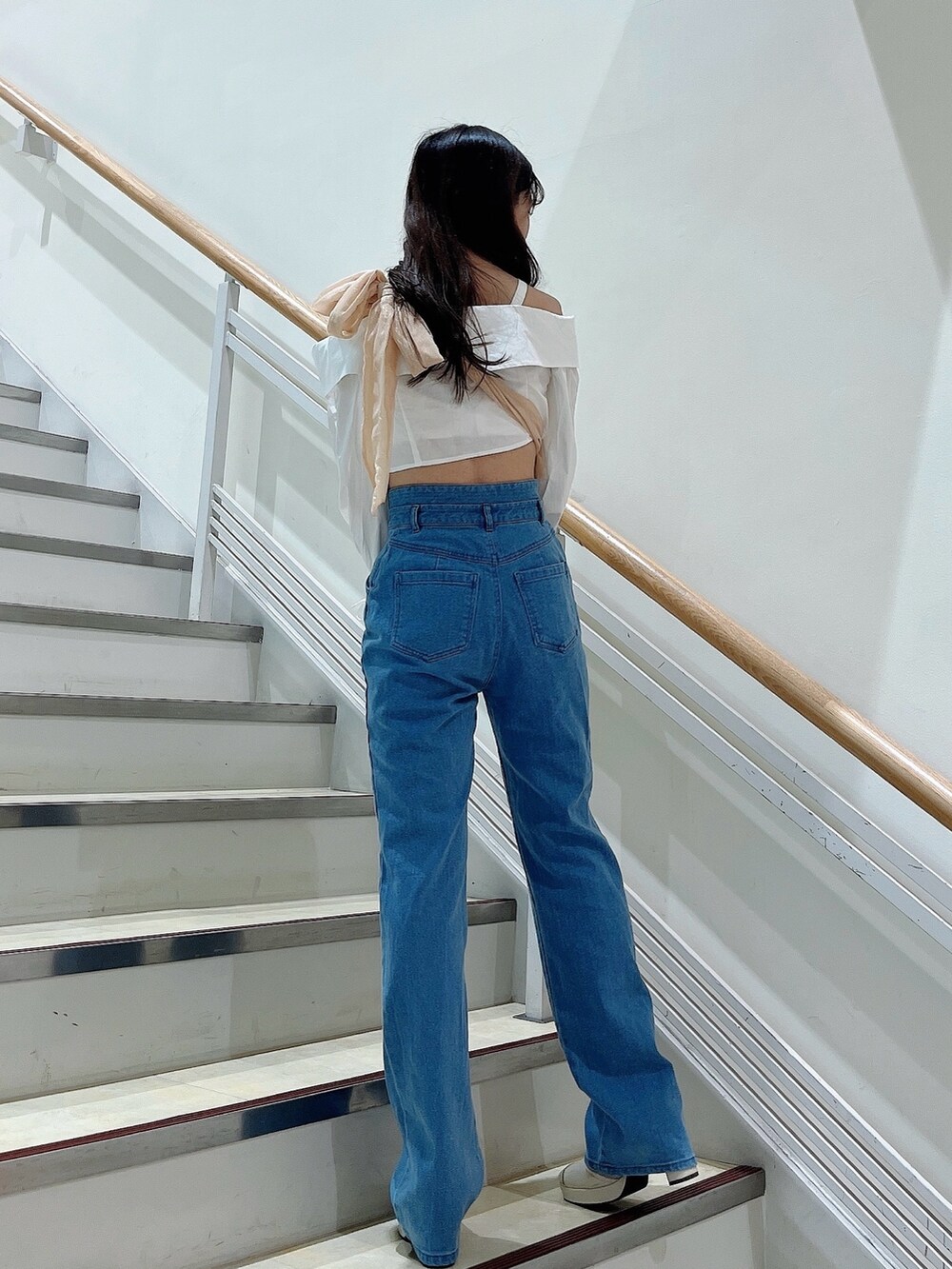 オレンジ系のベスト、ブルー系のデニムパンツ、ホワイト系のシャツ/ブラウスを着用したレディースの春コーディネートの4枚目の写真