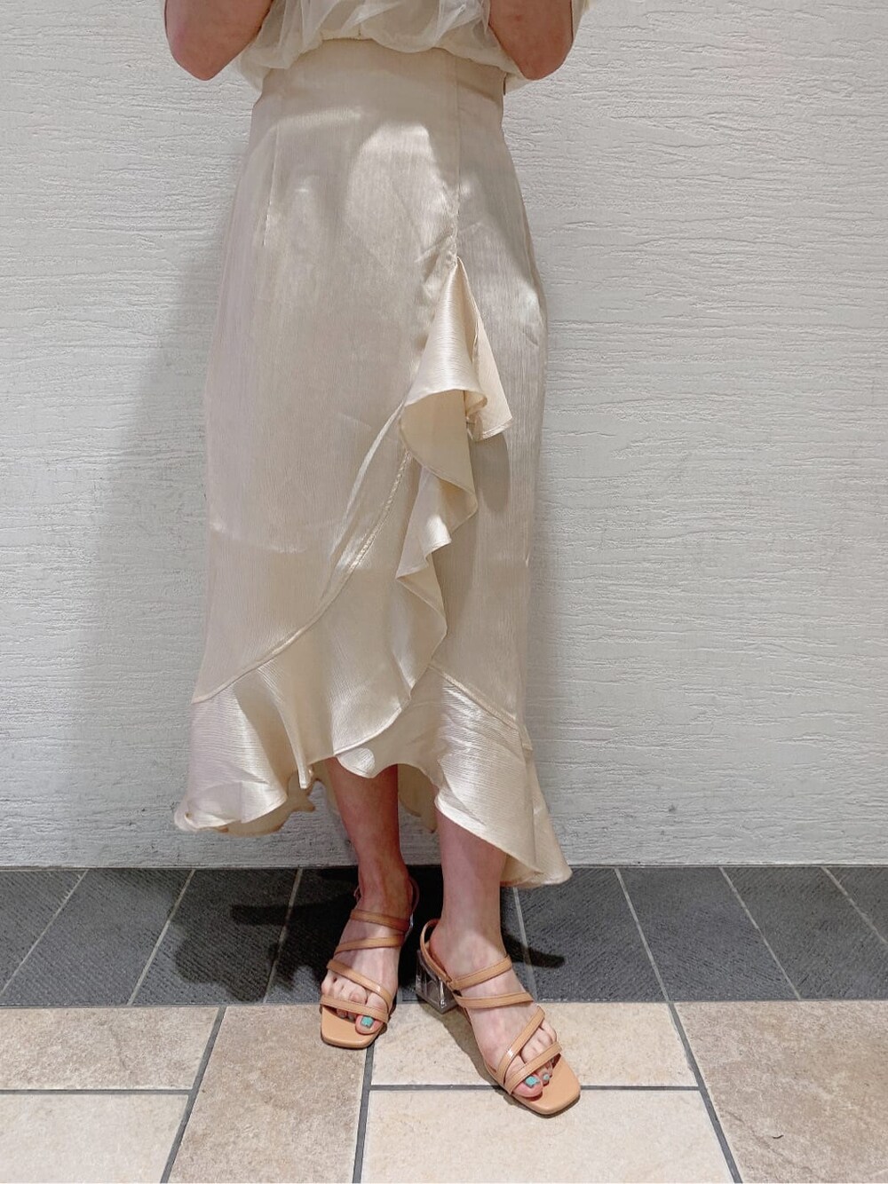 ホワイト系のスカート、ホワイト系のニット/セーター、オレンジ系のサンダルを着用したレディースの夏コーディネートの9枚目の写真