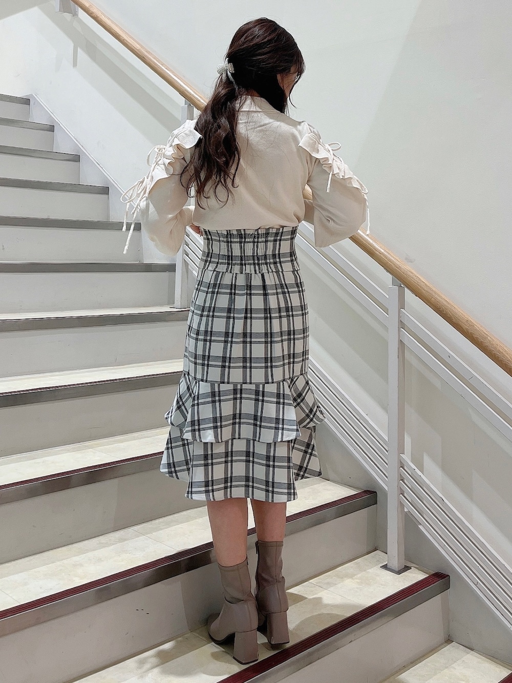 ホワイト系のニット/セーター、ホワイト系のスカート、ベージュ系のブーツを着用したレディースの冬コーディネートの4枚目の写真