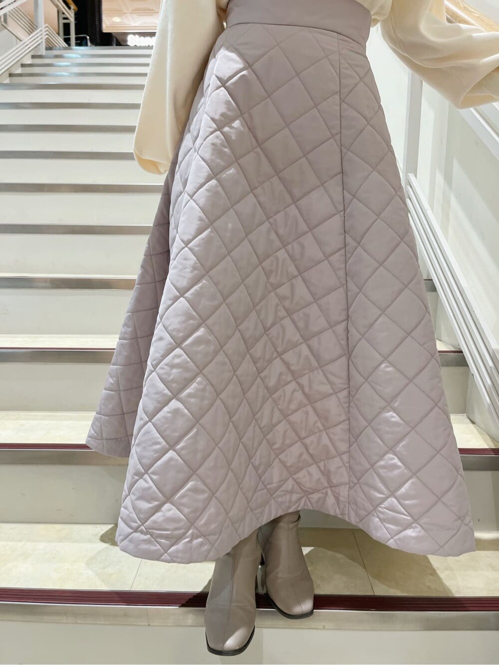 ホワイト系のニット/セーター、ピンク系のスカート、ベージュ系のブーツを着用したレディースの秋コーディネートの9枚目の写真