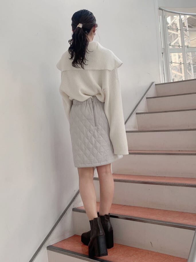 グレー系のスカート、グレー系のブーツ、ホワイト系のニット/セーターを着用したレディースの秋コーディネートの3枚目の写真