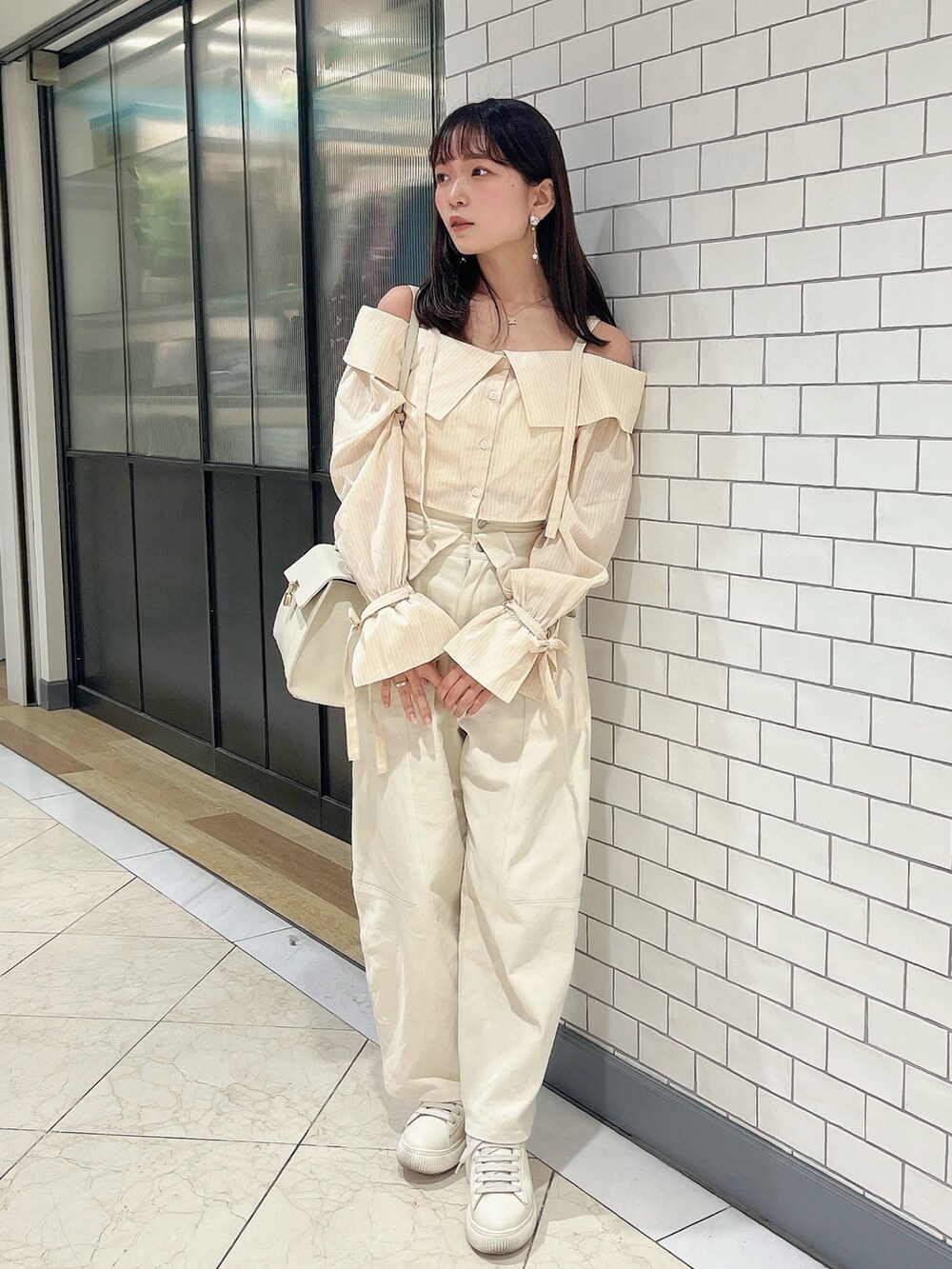 イエロー系のシャツ/ブラウス、ホワイト系のデニムパンツを着用したレディースの春コーディネートの2枚目の写真