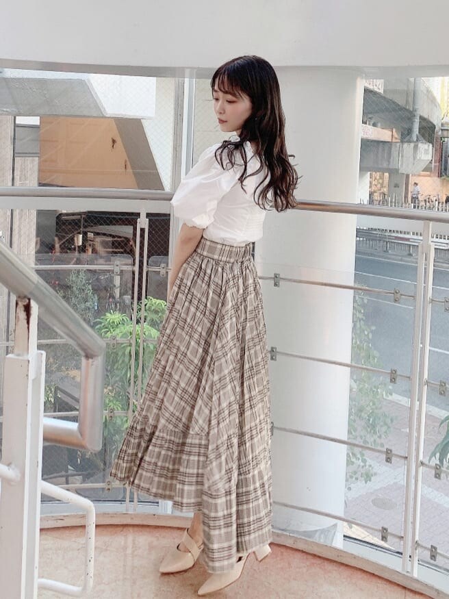 ホワイト系のシャツ/ブラウス、ベージュ系のスカート、ホワイト系のパンプスを着用したレディースの夏コーディネートの2枚目の写真