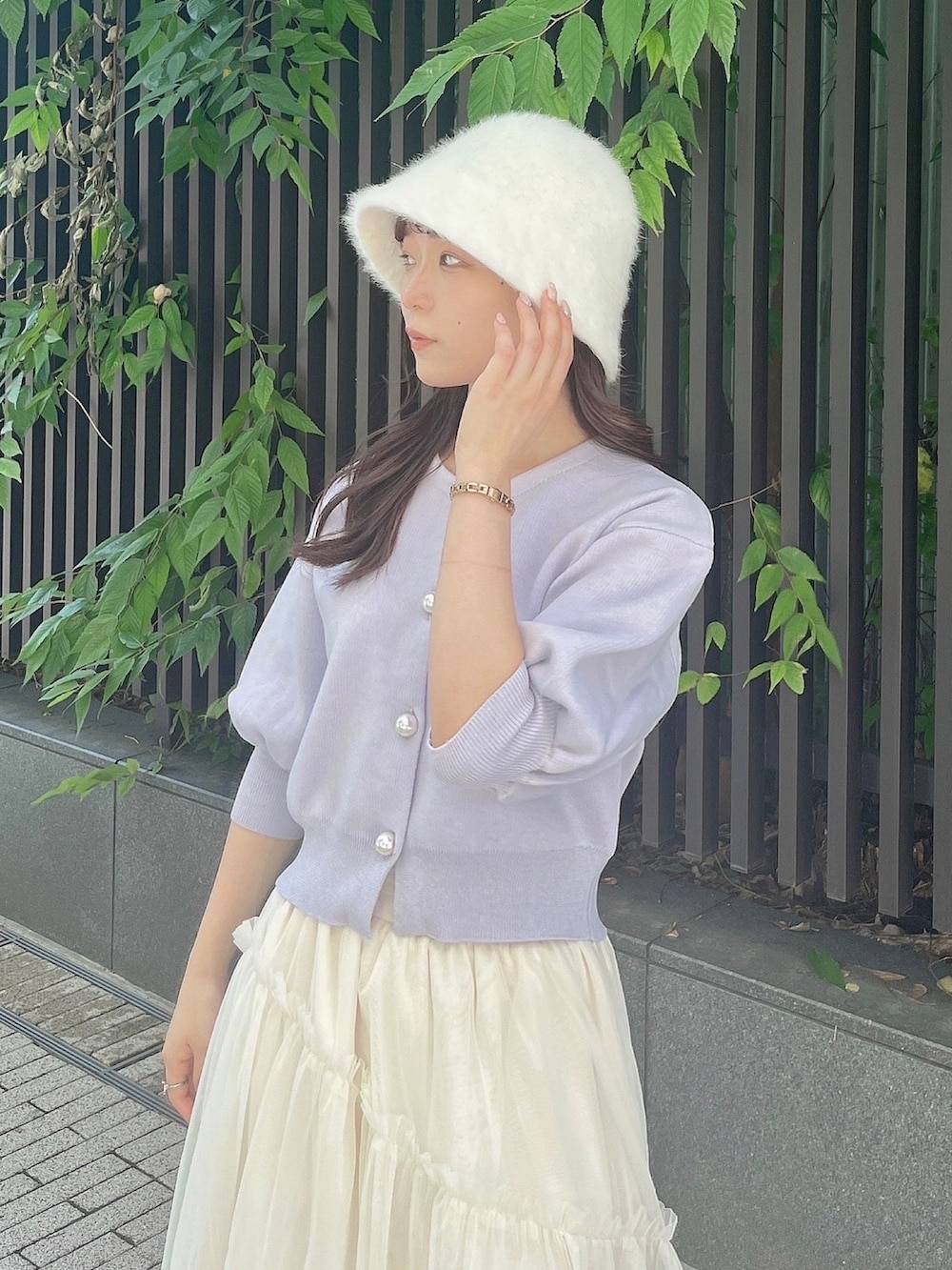 パープル系のカーディガン/ボレロ、ホワイト系のスカート、ホワイト系のブーツを着用したレディースの夏コーディネートの8枚目の写真