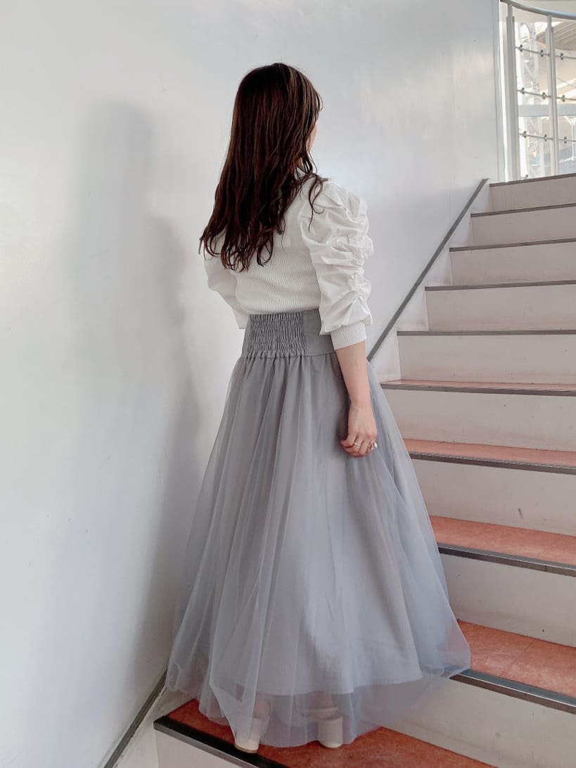 グレー系のスカート、ホワイト系のパンプス、ホワイト系のニット/セーターを着用したレディースの秋コーディネートの3枚目の写真