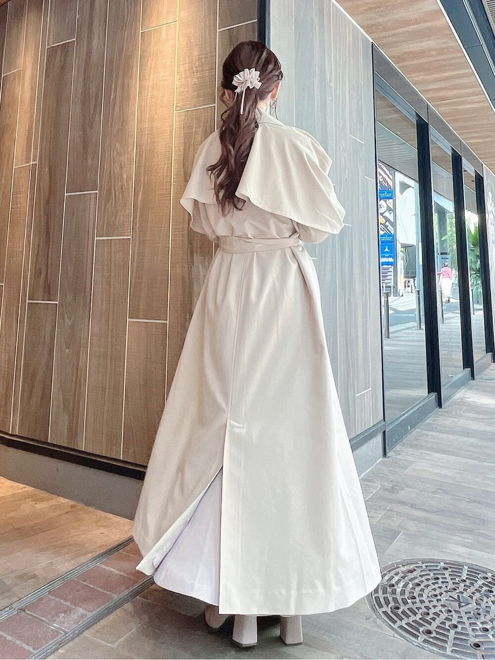 ベージュ系のトレンチコート、ベージュ系のブーツ、ベージュ系のスカートを着用したレディースの秋コーディネートの4枚目の写真