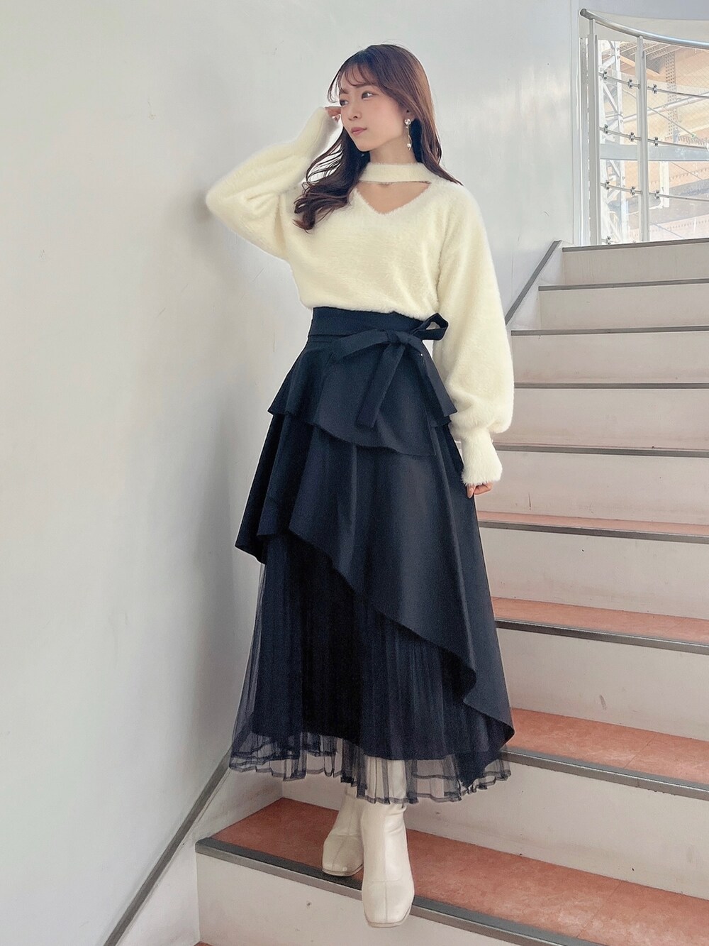 ホワイト系のブーツ、ブラック系のスカート、ホワイト系のニット/セーターを着用したレディースの秋コーディネートの2枚目の写真