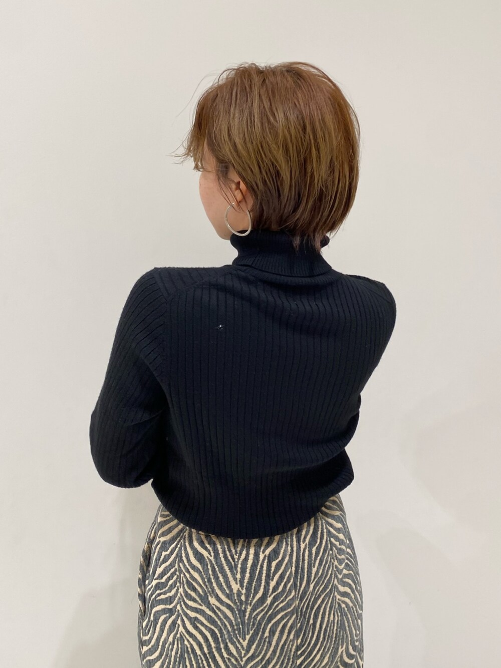ブルー系のスカート、ブラック系のニット/セーター、ブラウン系のムートンコートを着用したレディースの冬コーディネートの5枚目の写真
