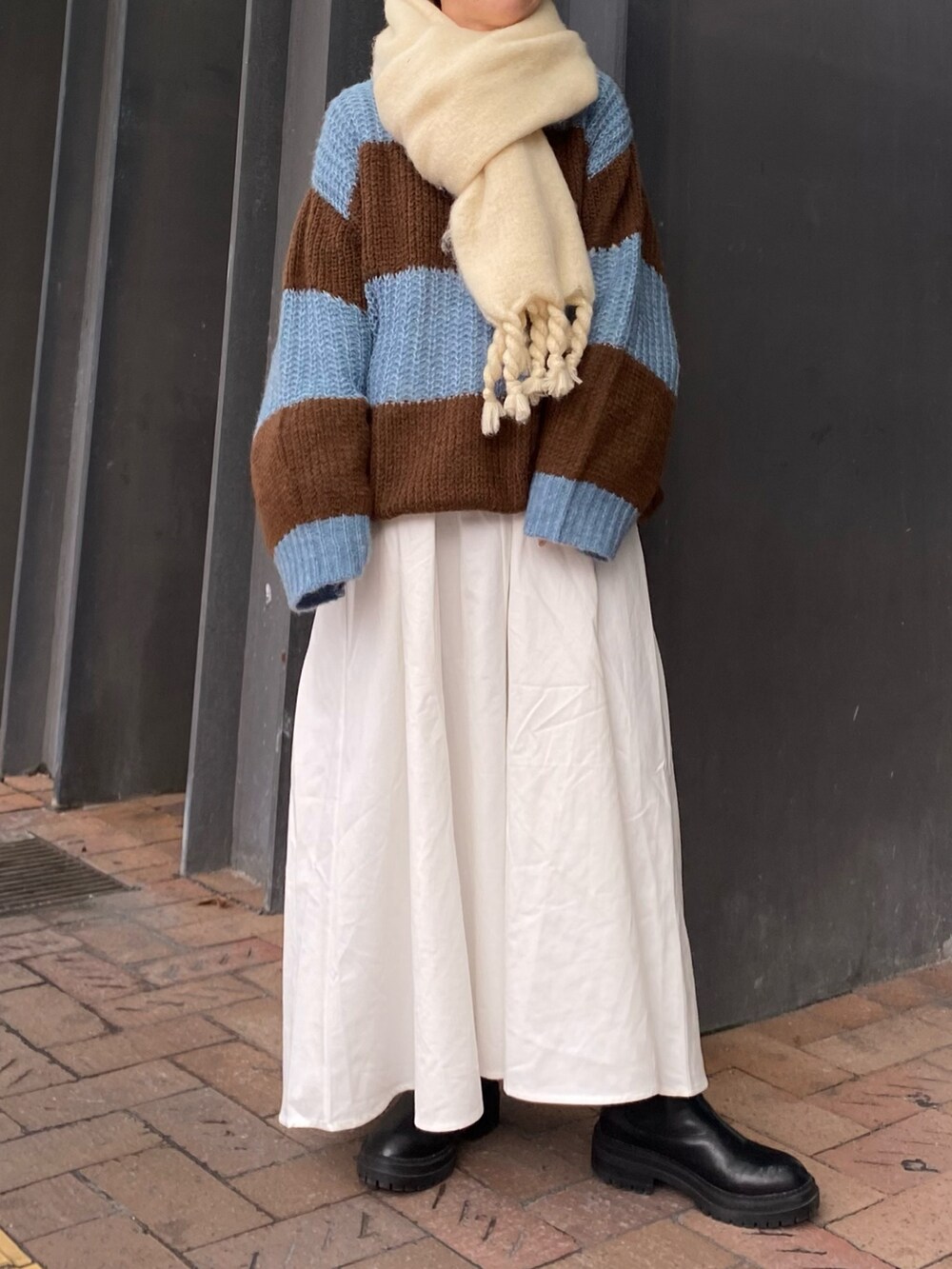 ブルー系のニット/セーター、ブラック系のワンピース、ホワイト系のマフラーを着用したレディースの秋コーディネートの2枚目の写真
