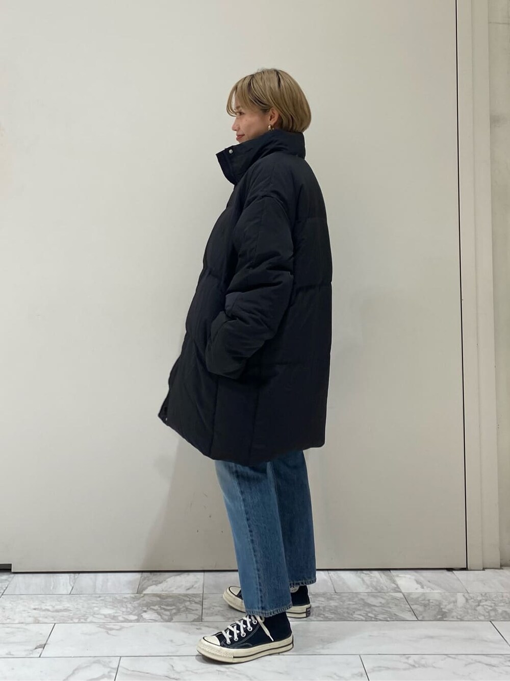 ブラック系のTシャツ/カットソー、ブルー系のデニムパンツ、ブラック系のダウンジャケット/コートを着用したレディースの秋コーディネートの2枚目の写真