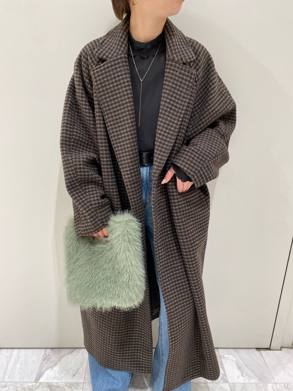 グリーン系のハンドバッグ、ブルー系のデニムパンツ、その他のチェスターコートを着用したレディースの冬コーディネートの2枚目の写真