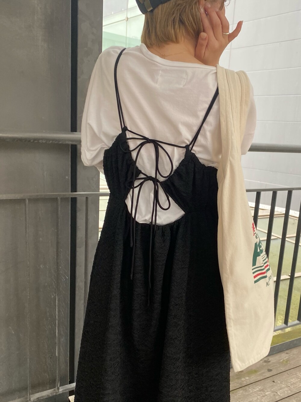 ブラック系のワンピース、イエロー系のパンプス、グリーン系のトートバッグを着用したレディースの春コーディネートの5枚目の写真