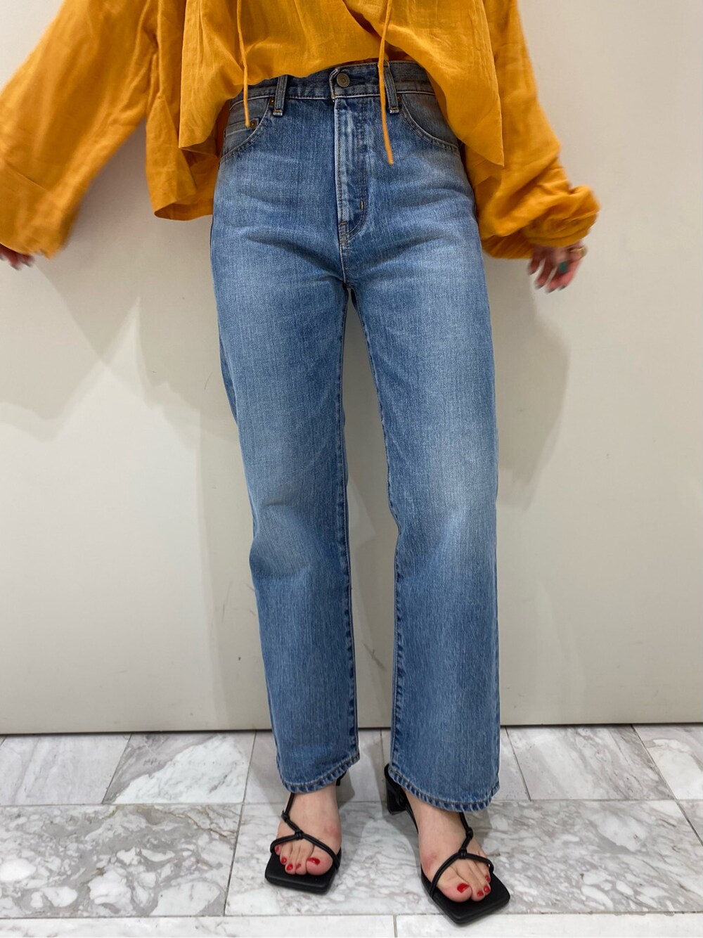 ブルー系のデニムパンツ、オレンジ系のシャツ/ブラウス、ブラック系のサンダルを着用したレディースの春コーディネートの7枚目の写真