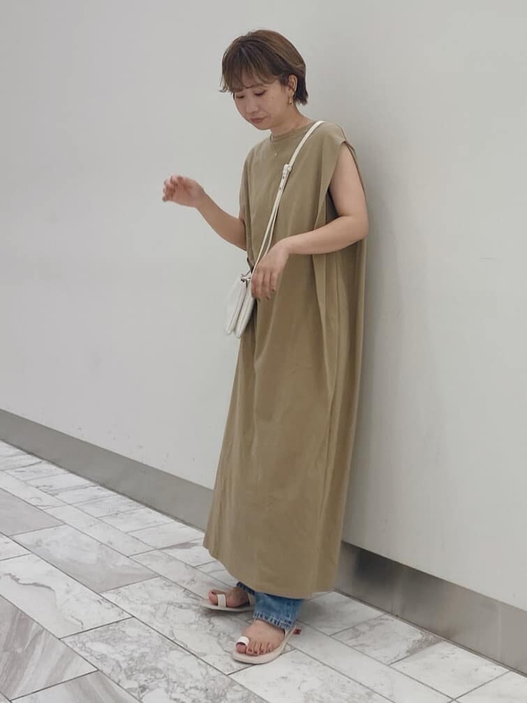 ベージュ系のワンピース、ホワイト系のサンダル、ブルー系のデニムパンツを着用したレディースの夏コーディネートの2枚目の写真