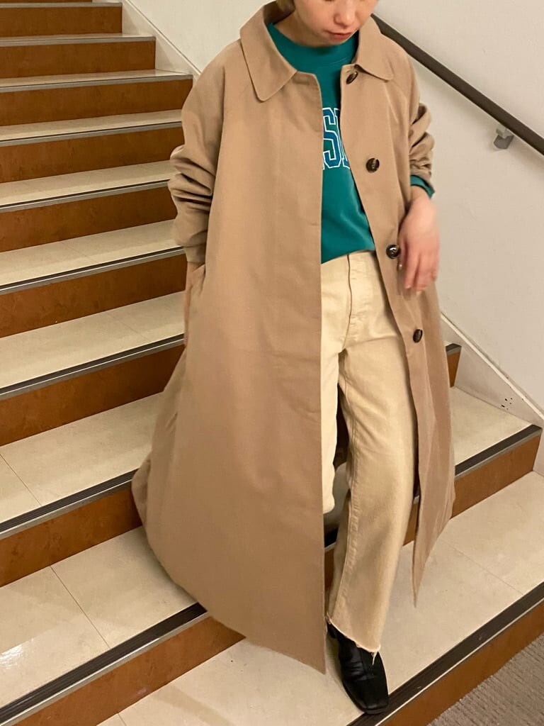 ベージュ系のステンカラーコート、グリーン系のスウェット、ホワイト系のデニムパンツを着用したレディースの冬コーディネートの6枚目の写真