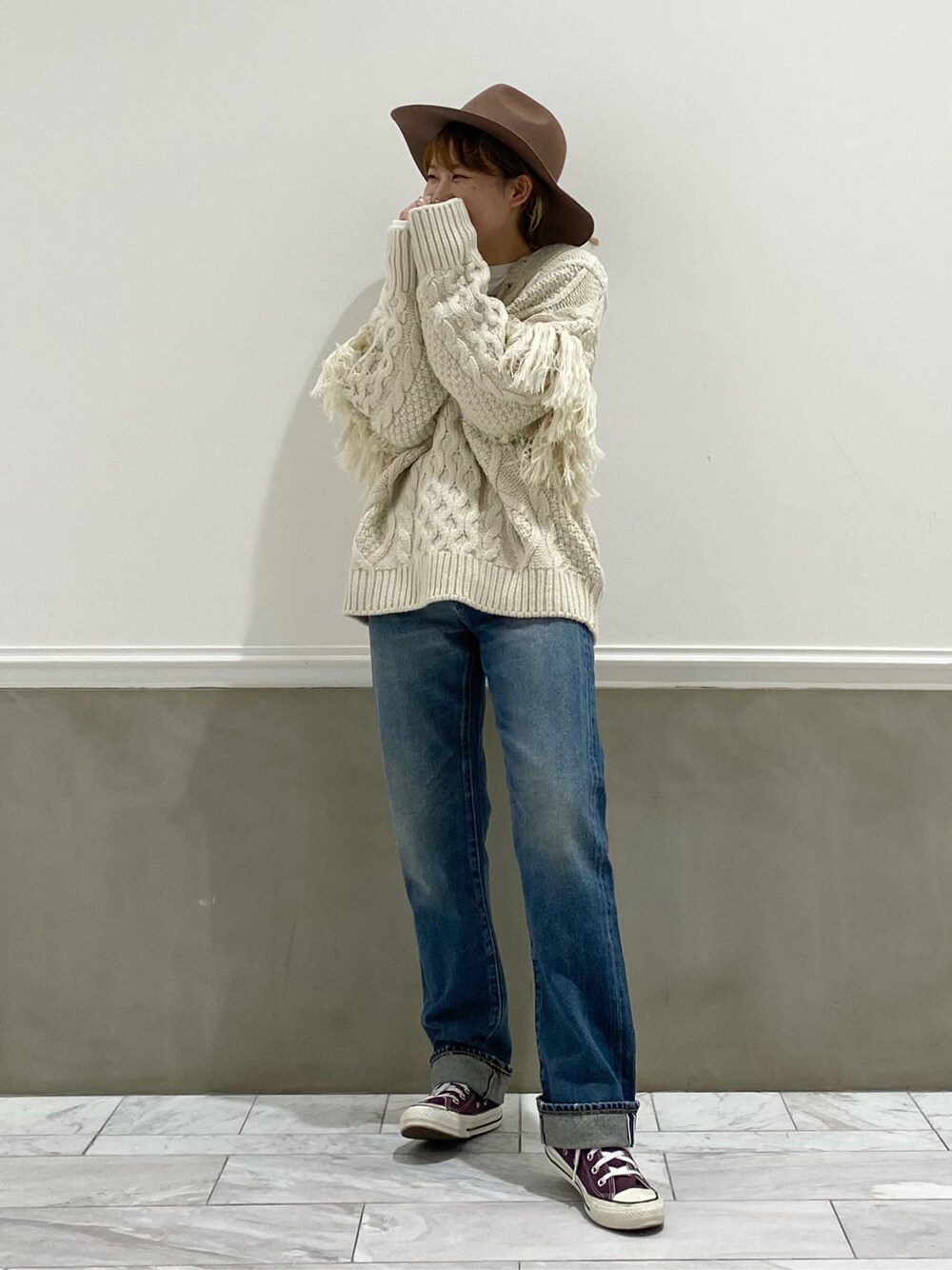 ブルー系のデニムパンツ、ホワイト系のニット/セーター、ホワイト系のTシャツ/カットソーを着用したレディースの冬コーディネートの2枚目の写真