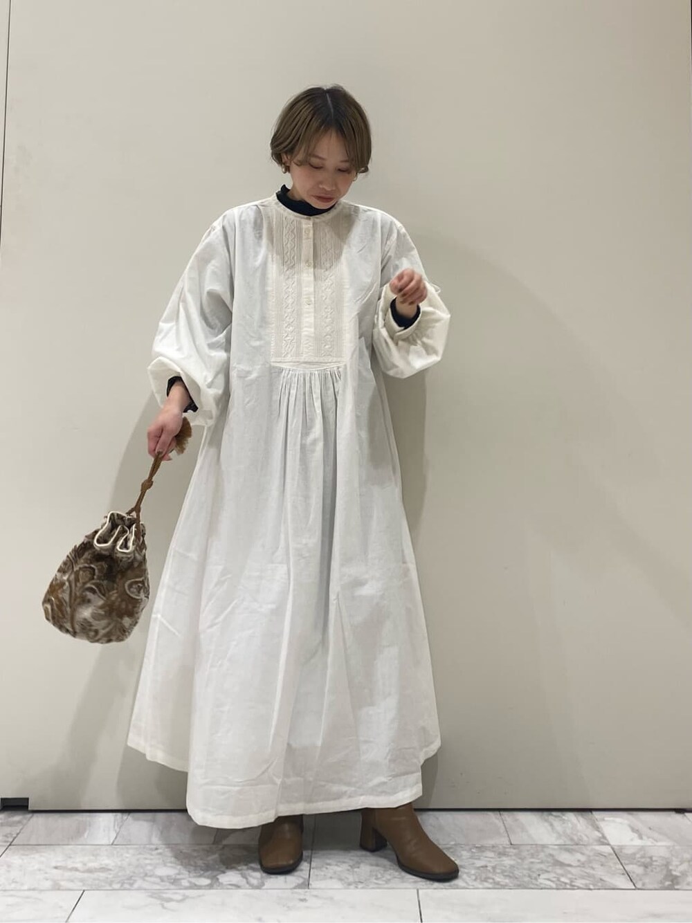 ホワイト系のハンドバッグ、ホワイト系のワンピースを着用したレディースの秋コーディネートの4枚目の写真