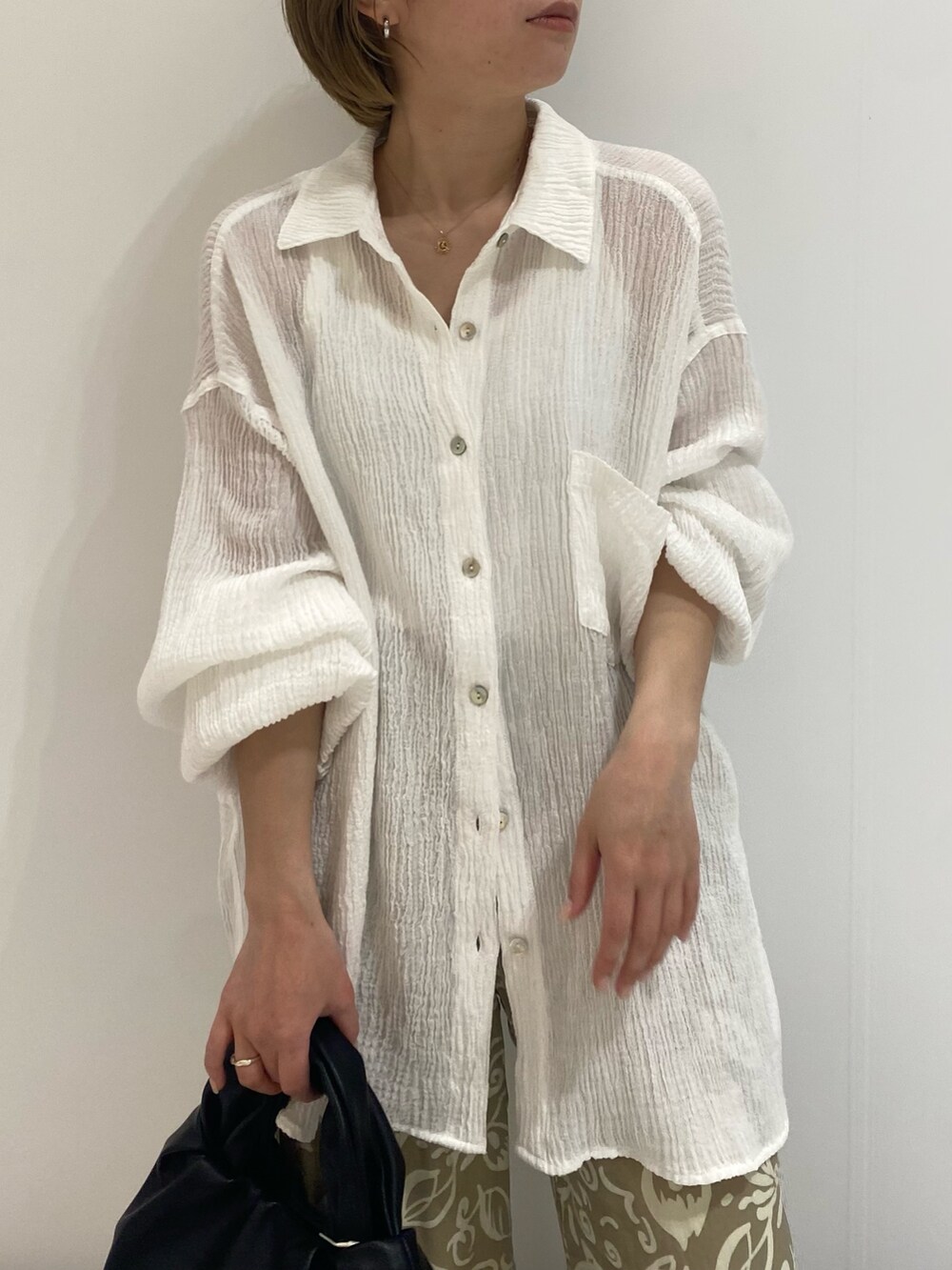 ブラック系のパンプス、ホワイト系のシャツ/ブラウス、ブラック系のハンドバッグを着用したレディースの春コーディネートの3枚目の写真